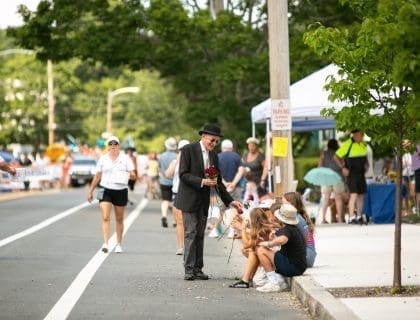 Male Magician with a Black Hat Entertaining People on the Sidewalk at a Newburyport MA Street Fair