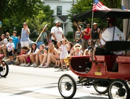 Crowd watching a Red Highwheeler ride down the street in Newburyport's Annual Yankee Homecoming Parade