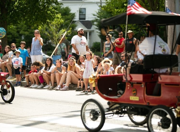Crowd watching a Red Highwheeler ride down the street in Newburyport's Annual Yankee Homecoming Parade