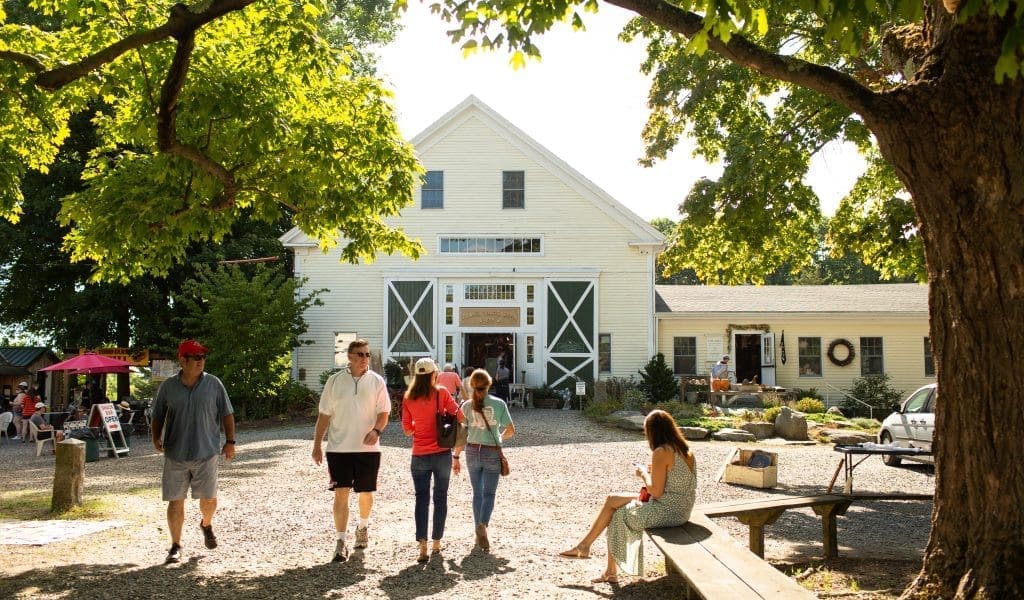 People Walking Past the White Cottage at Todd Farm Flea Market in Rowley MA