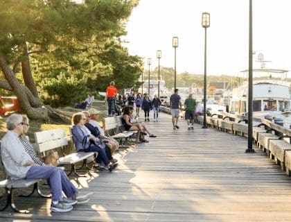 People Sitting on Benchs. and walking along the sidewalk overlooking the Merrimack river