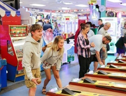 Six casually dressed people of all different ages playing skeeball together in the arcade at Joe's Playland in Salisbury MA
