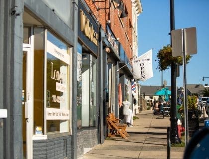 View of lively Humphrey Street in Swampscott MA filled with shops on a clear blue sky summer day