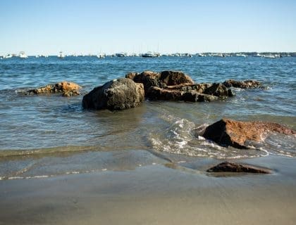 View of large rocks in the water on a clear blue sky day at Fisherman's Beach in Swampscott MA