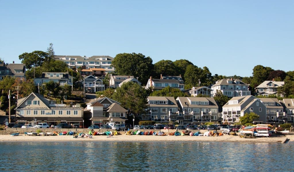 View of Fisherman's Beach filled with people and the residential neighborhood behind it on a beautiful clear day with blue skies in Swampscott MA