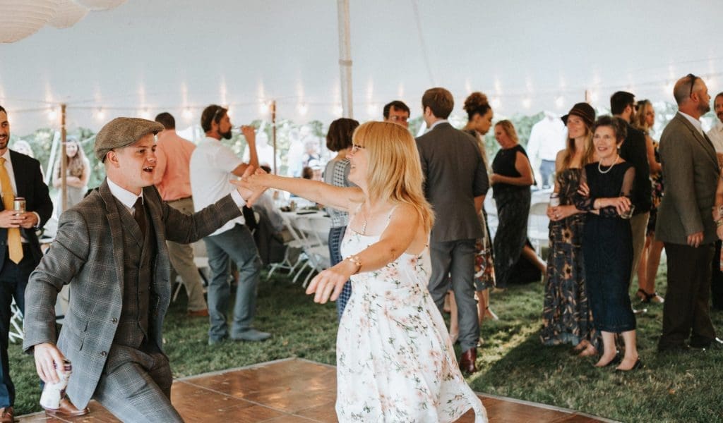 A man and a woman dancing on the dance floor under an white event tent.