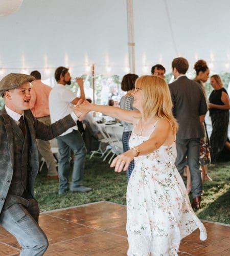 A man and a woman dancing on the dance floor under an white event tent.