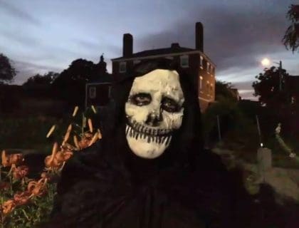 A person posing at night wearing a skeleton mask