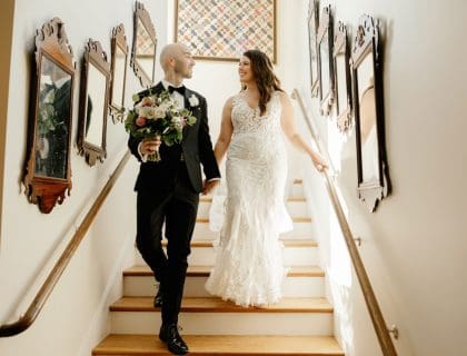 Groom and bride walking down stairs holding hands.