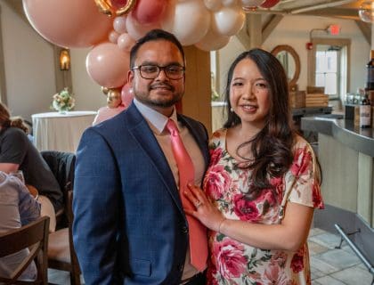 A couple at a baby shower with balloons.