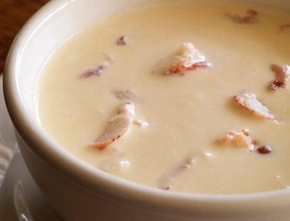 A cropped close-up photo of freshly made lobster bisque in a white bowl with saucer from Turner's Seafood in Salem, MA.