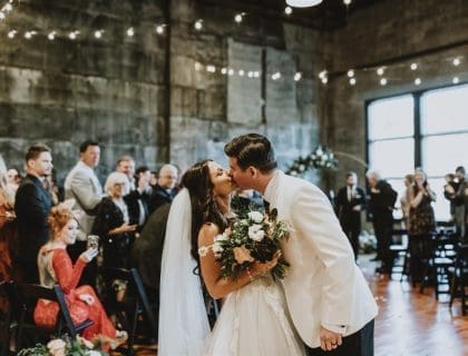 A couple kisses at the end of the aisle after their wedding ceremony at Olio in Peabody, Massachusetts