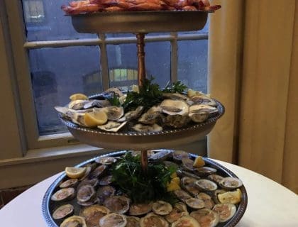 A 3-tier seafood tower in front of a dim-lit window at Turner's Seafood in Salem, MA.